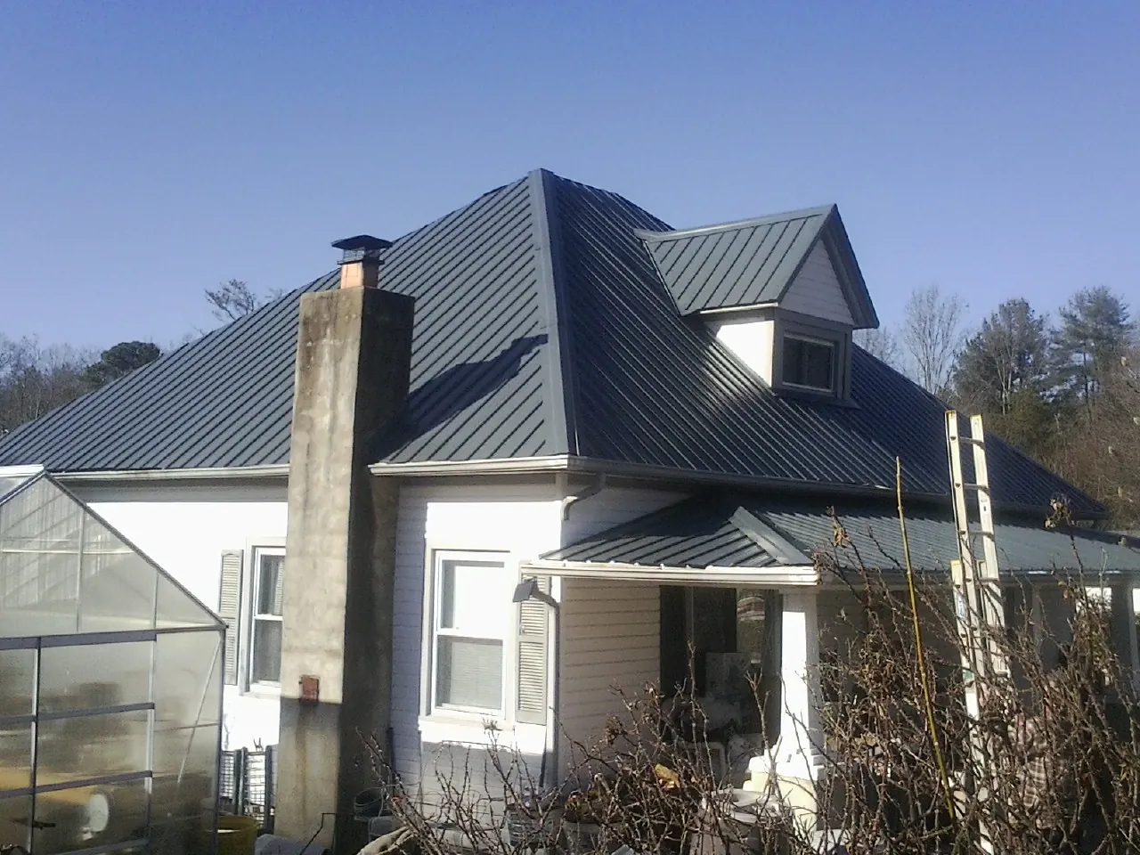 Dark blue standing seam metal roof on a white farmhouse with dormer — Slate & Tile Roof Repair by Roofing Brothers in Park