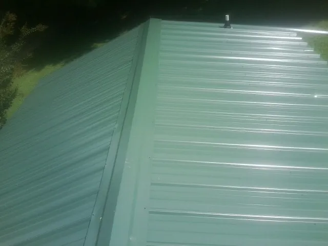 New green metal panels meeting at the ridge of a roof — Flat Roof Repair work by our crew in Park
