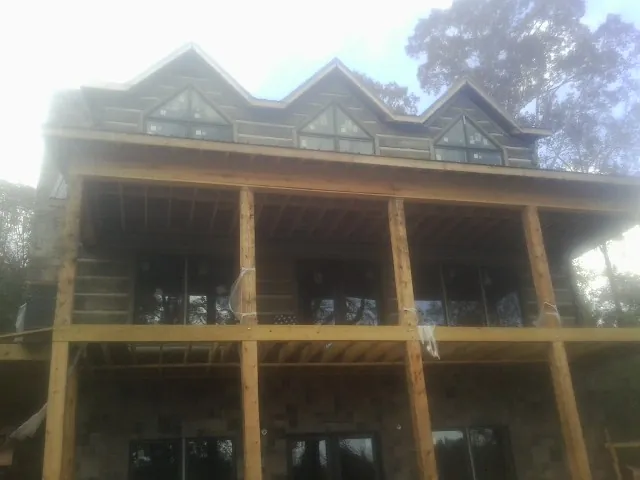 Dormers and porch framing on a large log home under construction — Roof Coating work by our crew in Park