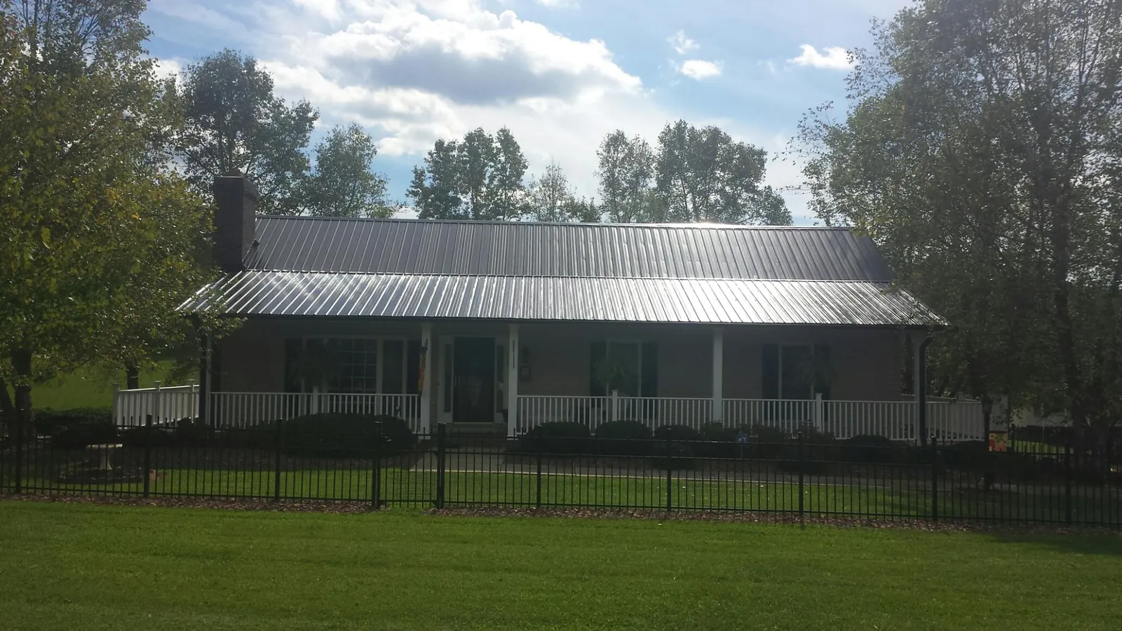 Gray metal roof on a brick ranch with a full width front porch — Gutter Guard Installation work by our crew in Park