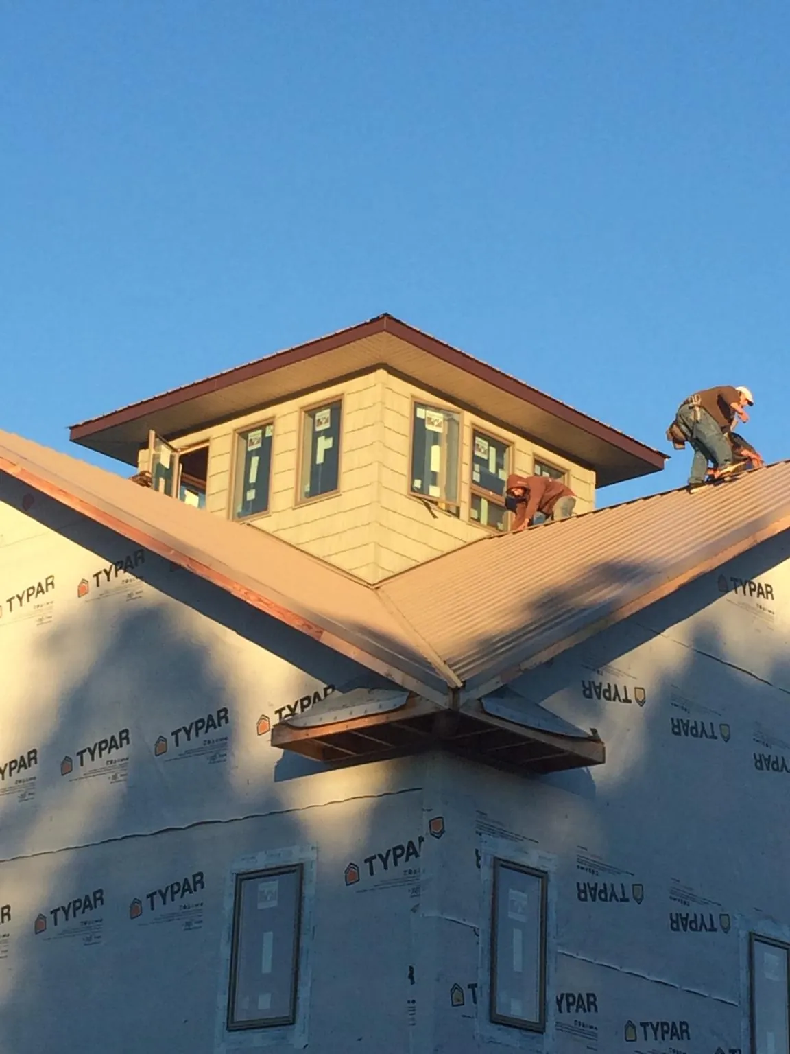 Roofers working around a rooftop cupola on a new metal roof at sunset — Roof Waterproofing in Park by Roofing Brothers